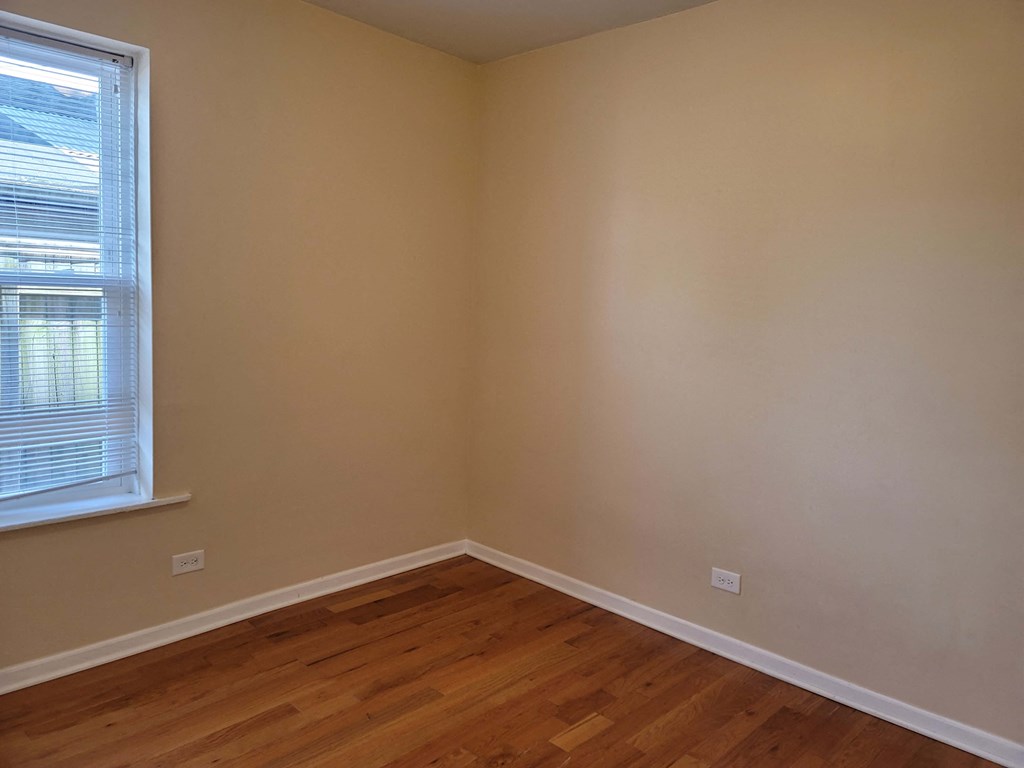 the corner of a room with wooden floors and a window