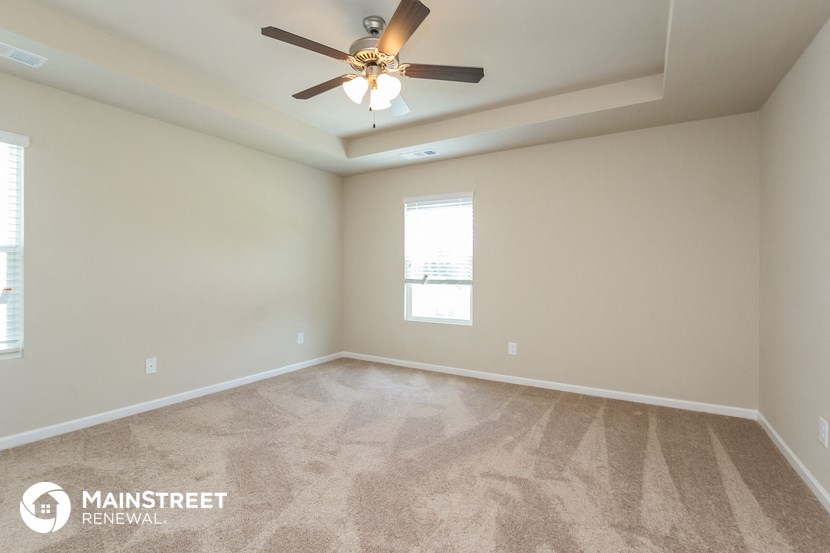 the spacious living room with carpeting and a ceiling fan