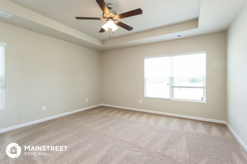an empty living room with a ceiling fan and a window