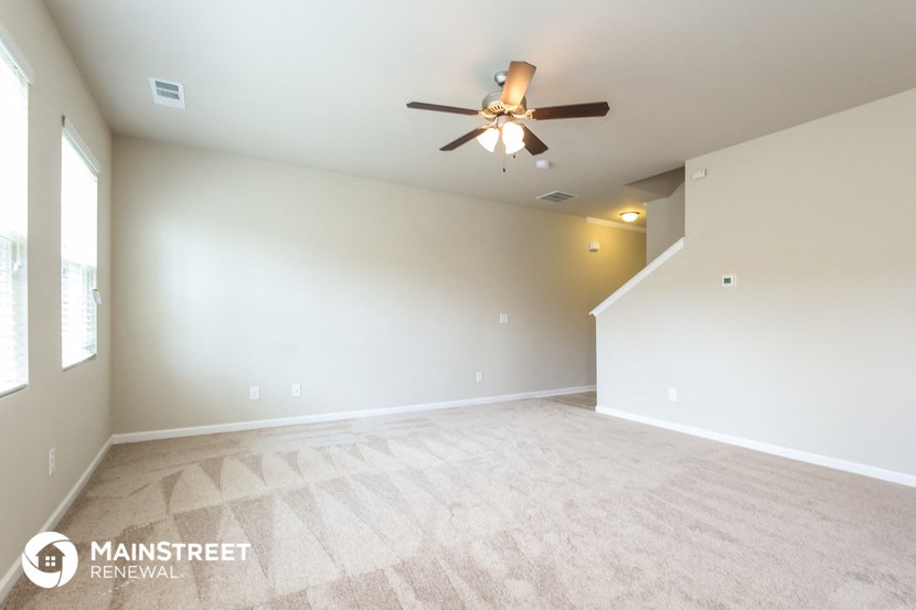 the spacious living room and dining room with ceiling fan