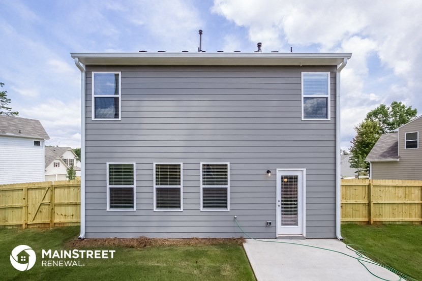 the front of a house with a driveway and a wood fence