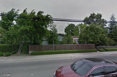 a red car parked on a street in front of a house