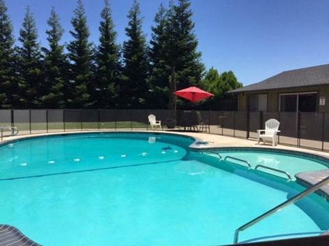 a large swimming pool with chairs and a umbrella