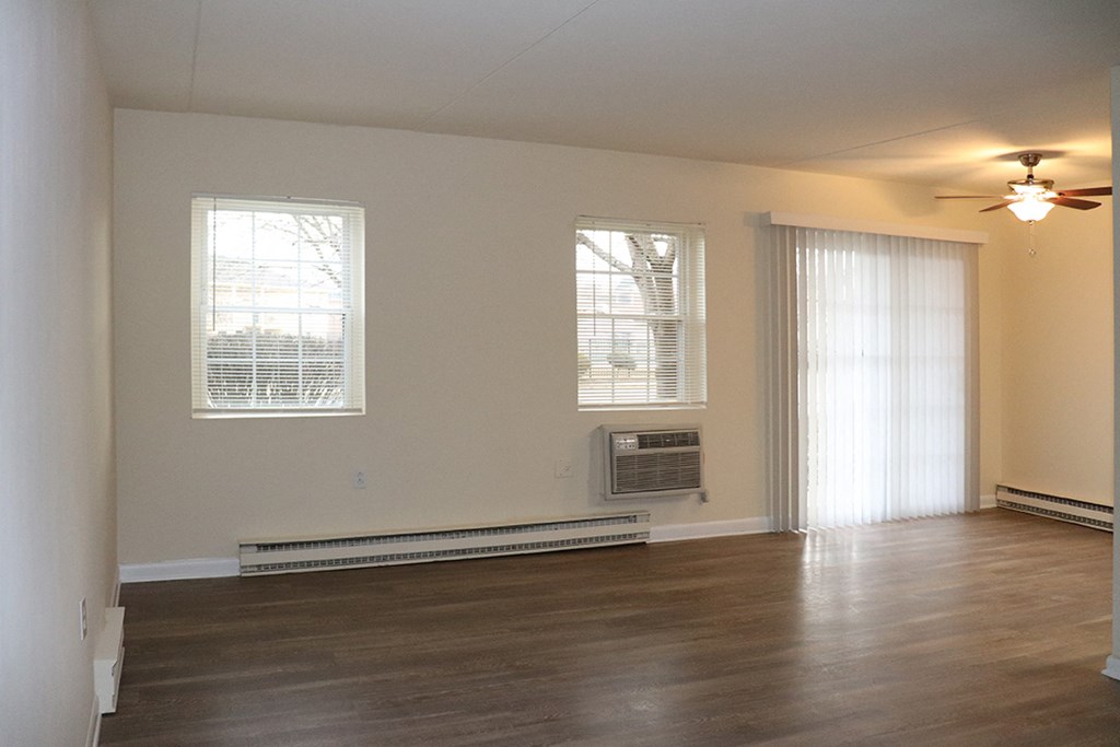 an empty living room with a ceiling fan and a window