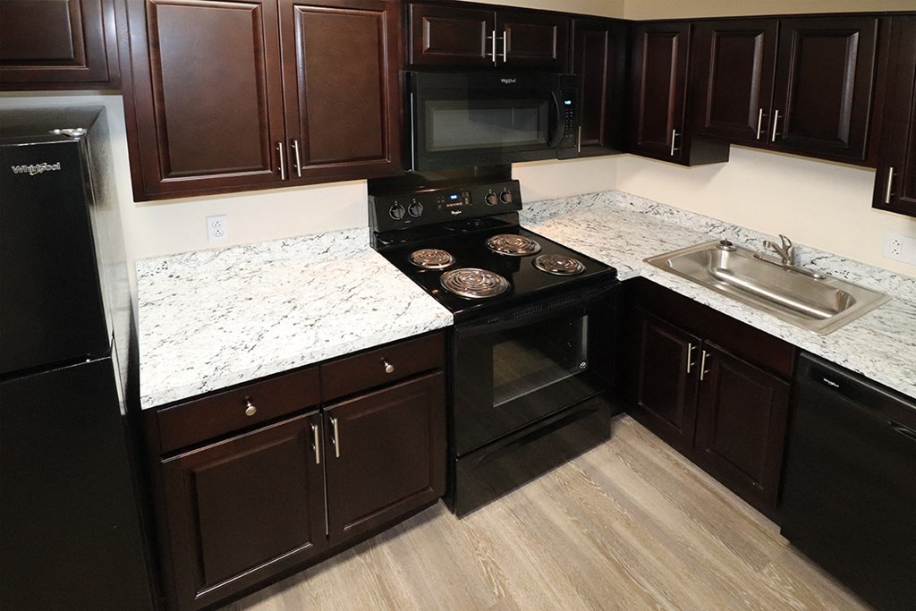 an updated kitchen with marble counter tops and black appliances