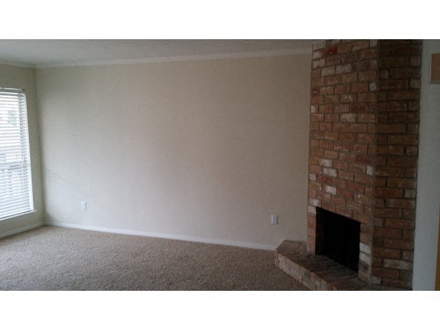 an empty living room with a brick fireplace