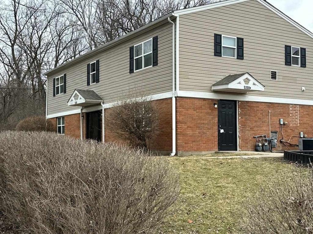 A two-story house with a black door and a covered patio.