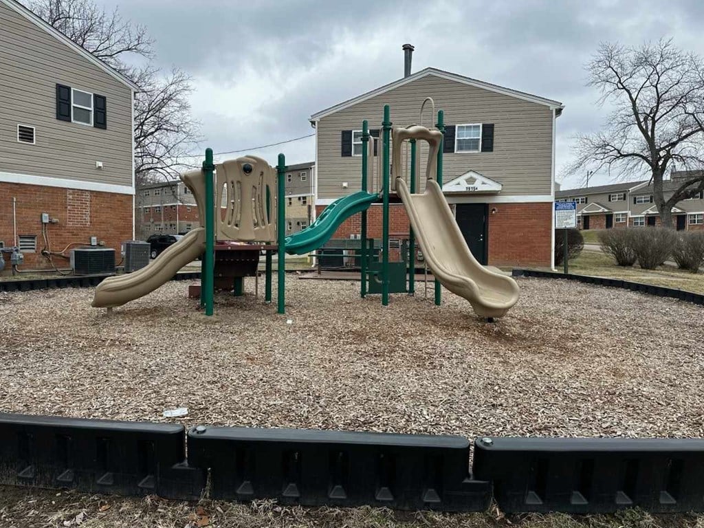 A playground with a green slide and a tan slide.