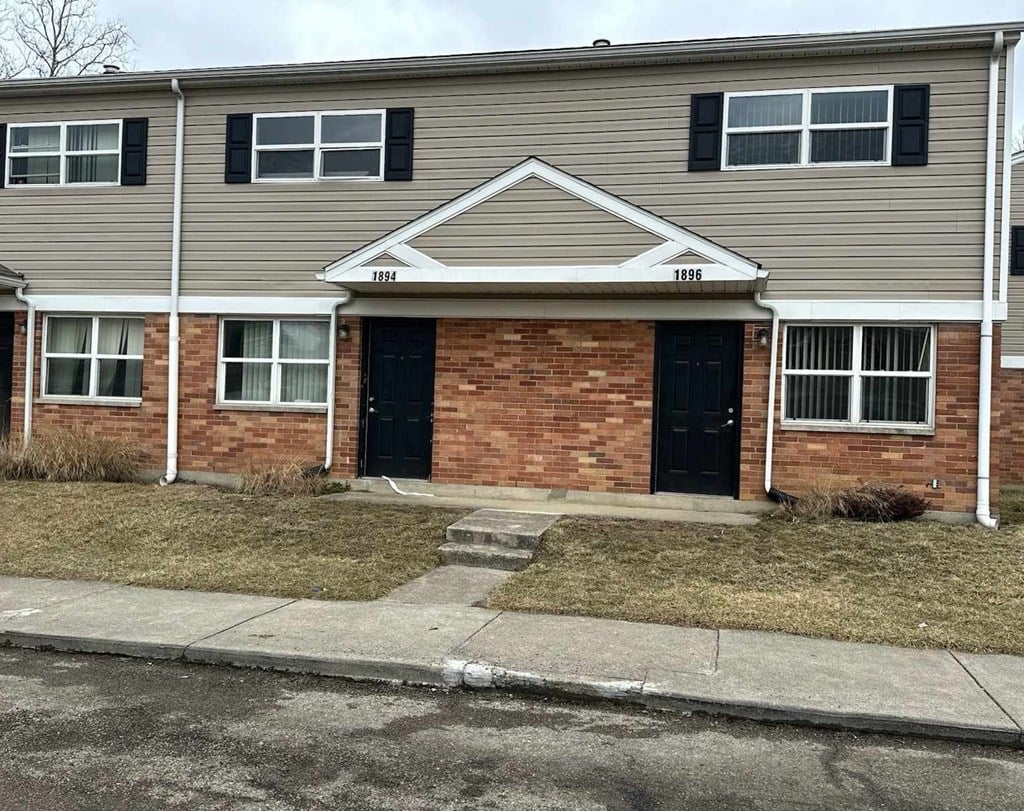 A brick house with a black door and a small front yard.