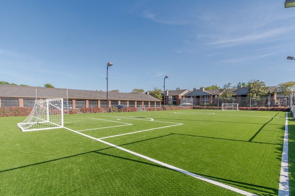 a soccer field with a soccer goal on it in front of a building