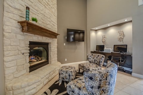 a living room with a stone fireplace and chairs