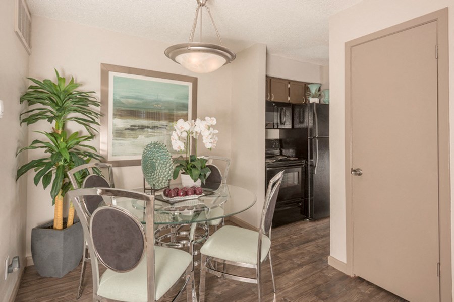 a dining room with a glass table and chairs and a kitchen