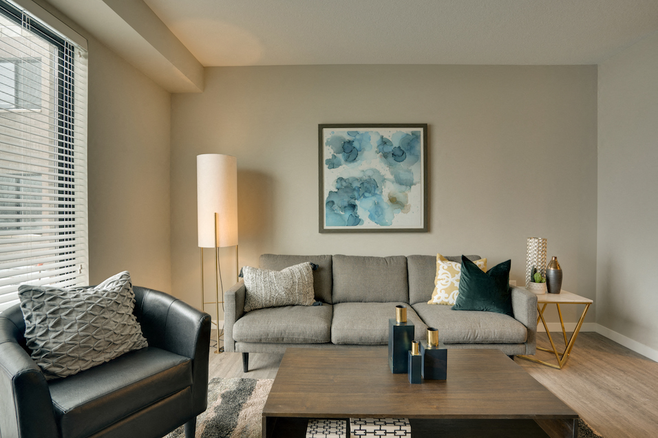 Living room with a black leather chair, a gray sofa, and blue floral painting on the wall