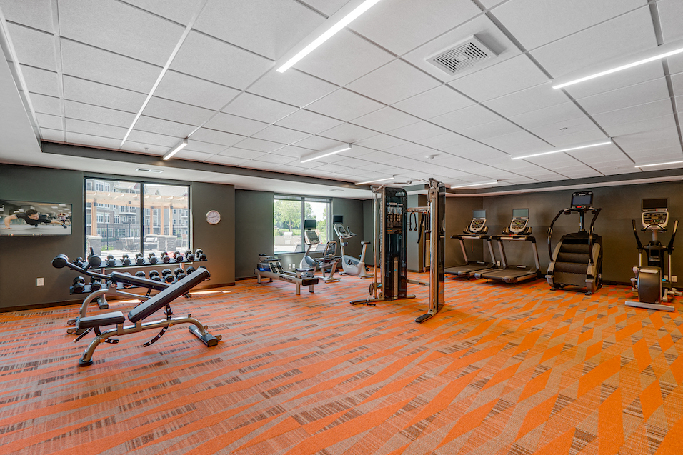 a workout room with weights and other equipment in a large room with windows