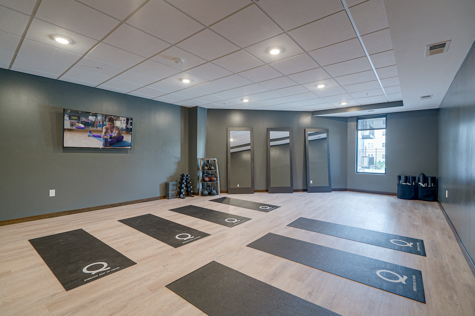 a workout room with yoga mats on the floor and a tv on the wall