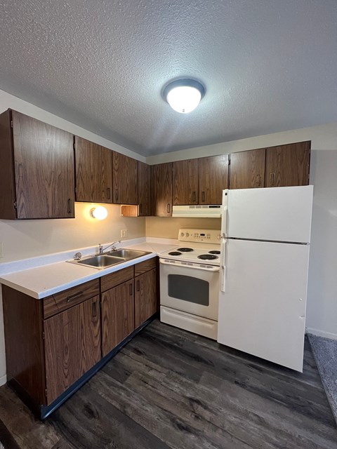 A kitchen with white appliances and wooden cabinets.
