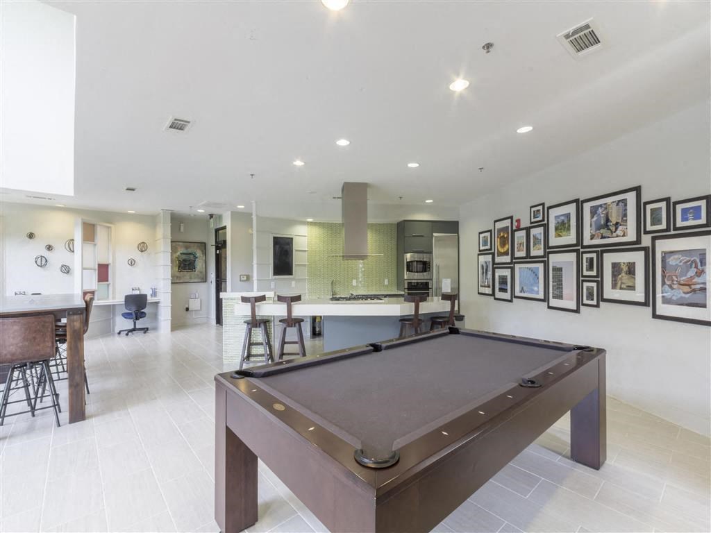 a pool table in a living room with a bar and a kitchen