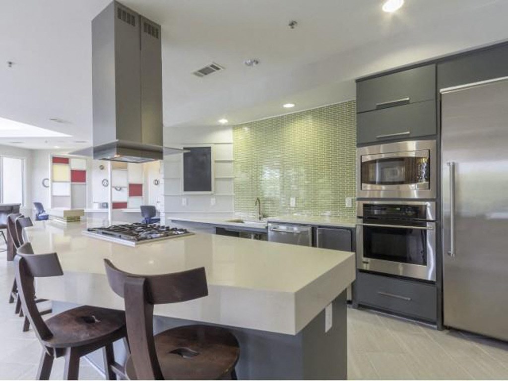 a large kitchen with a white counter top and stainless steel appliances