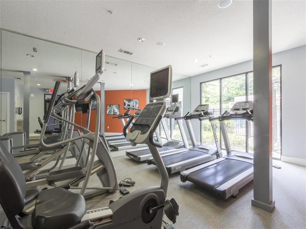 the gym is equipped with cardio equipment and a large window