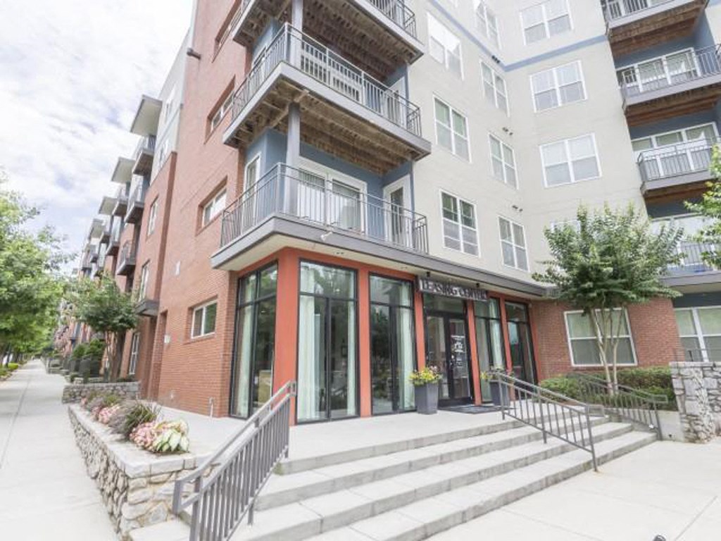 the front of an apartment building with stairs and a sidewalk