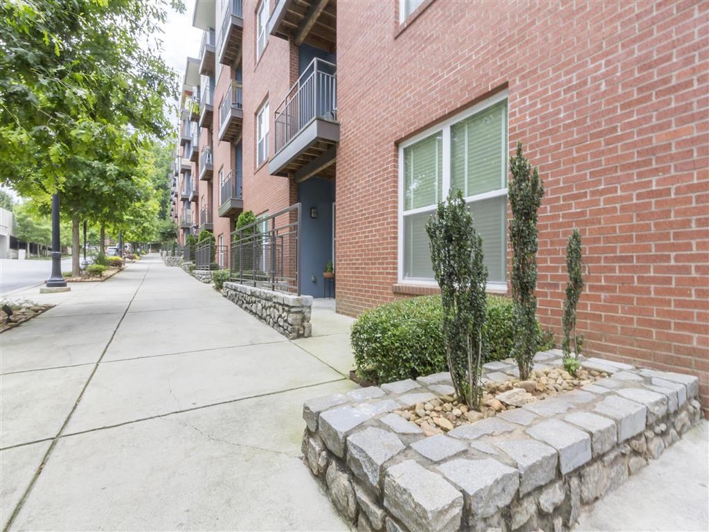 an empty sidewalk in front of a brick apartment building