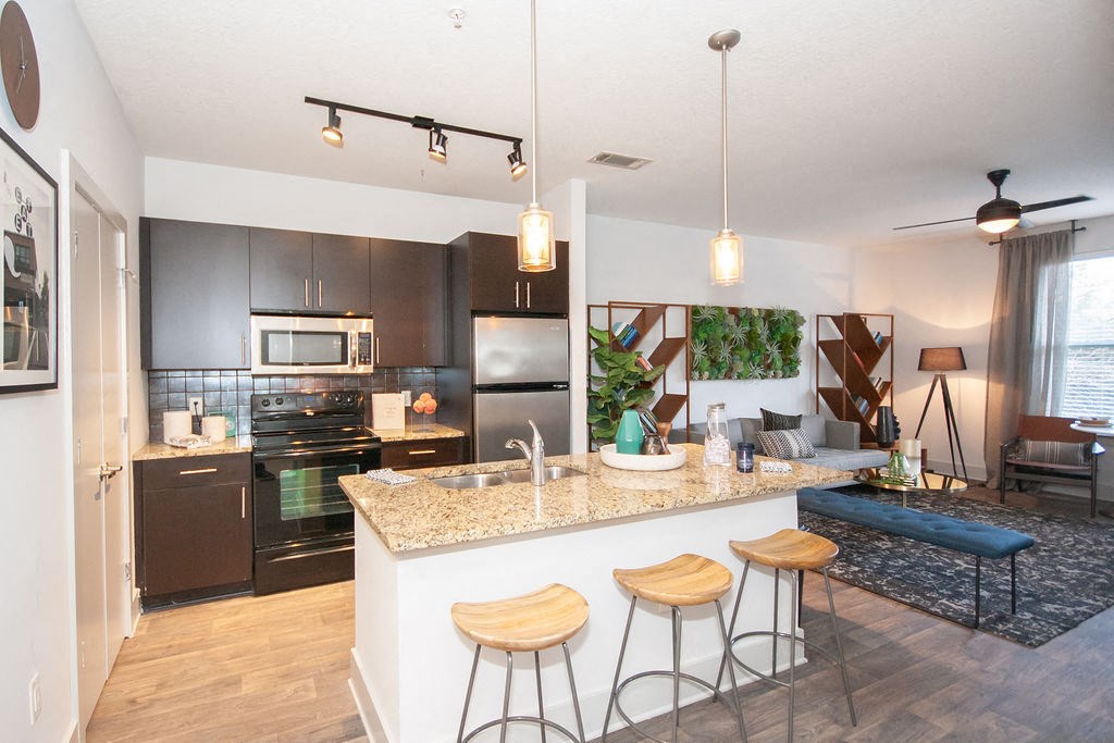 an open kitchen and living room with a bar and stools