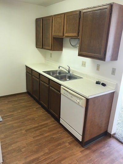 A kitchen with wooden cabinets and a white dishwasher.