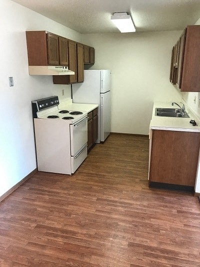 A kitchen with a stove, refrigerator, and sink.