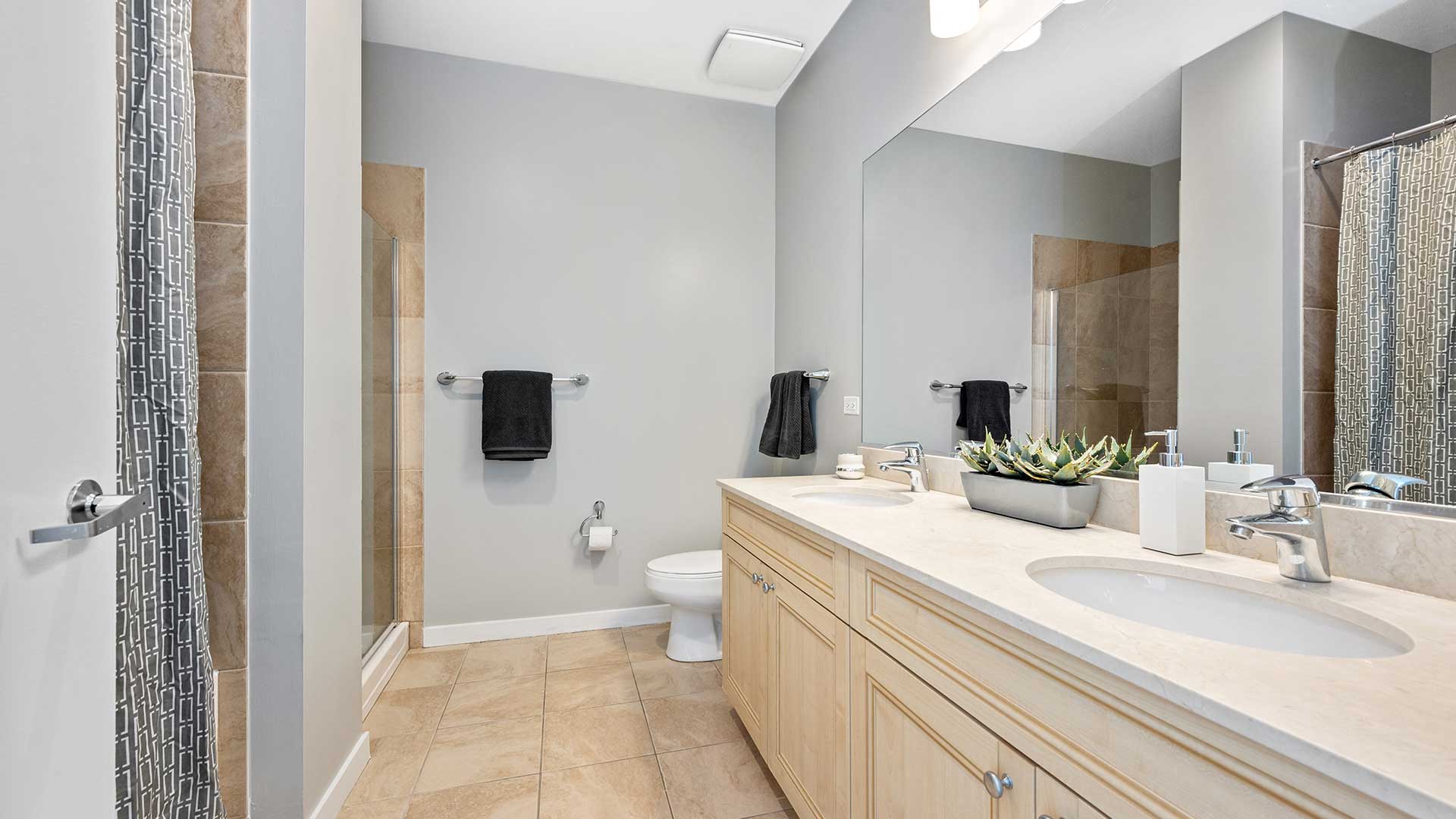 Looking into a bathroom in a residence at Burnham Pointe. The vanity runs along the right wall, followed by the toilet. The shower is back on the left.