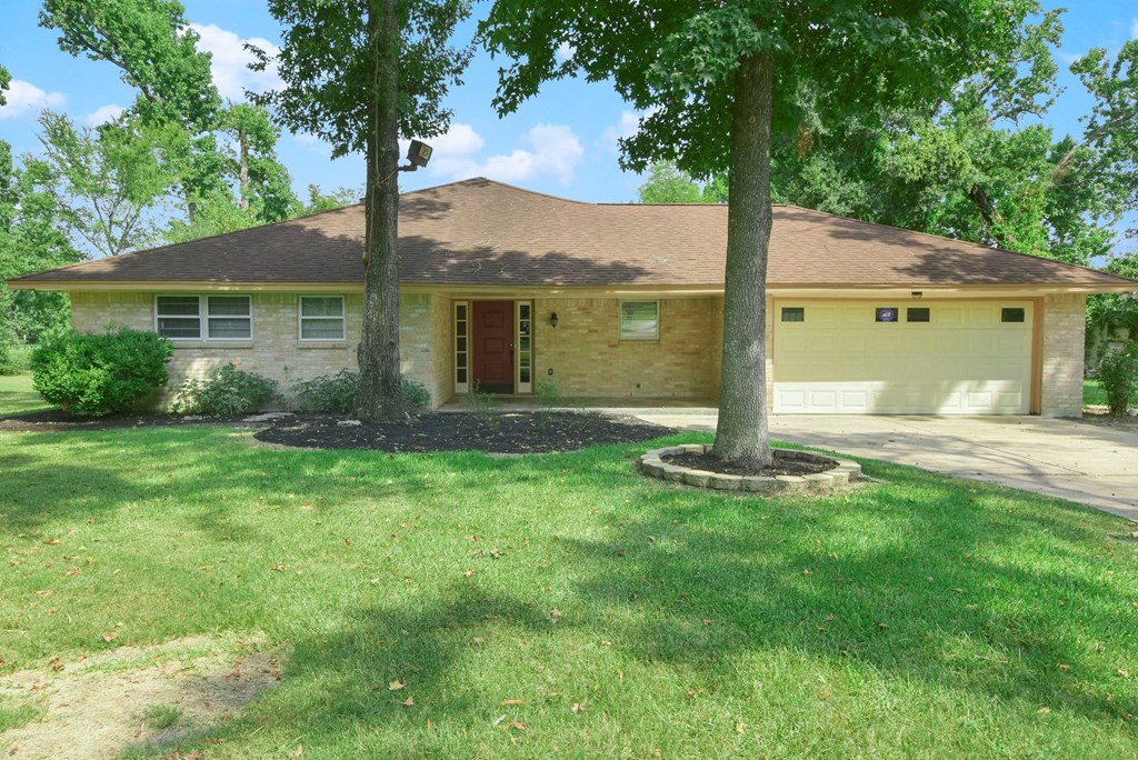 a small yellow house with a lawn and trees