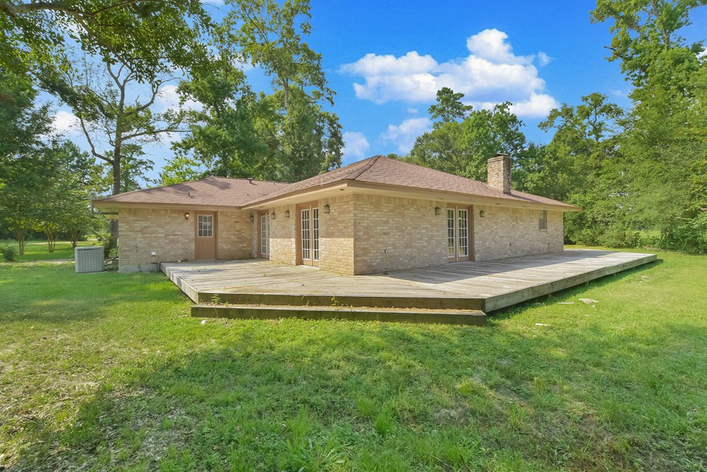 a small brick house with a deck in the grass