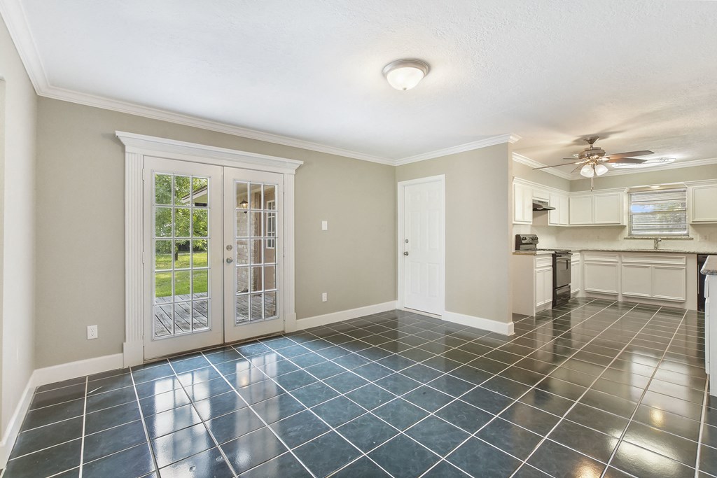 the living room and kitchen of an empty house with a ceiling fan