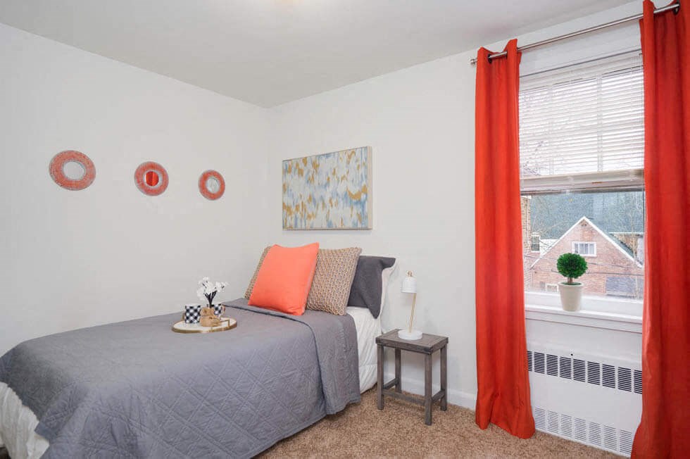 a bedroom with a bed and a window with orange curtains