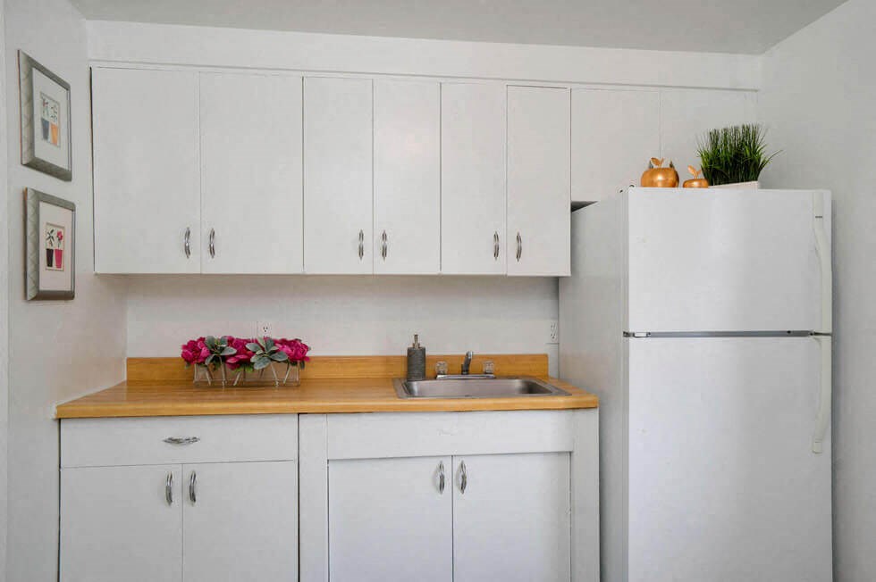 a kitchen with white cabinets and a sink and a refrigerator