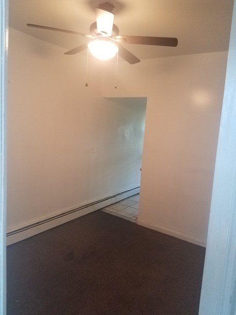 A room with a ceiling fan and a door.