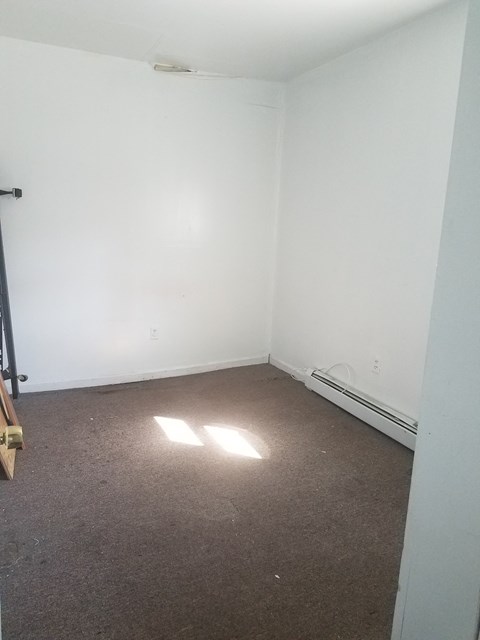 A room with a carpeted floor and a window letting in sunlight.