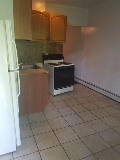 A kitchen with a white refrigerator, black stove, and wooden cabinets.