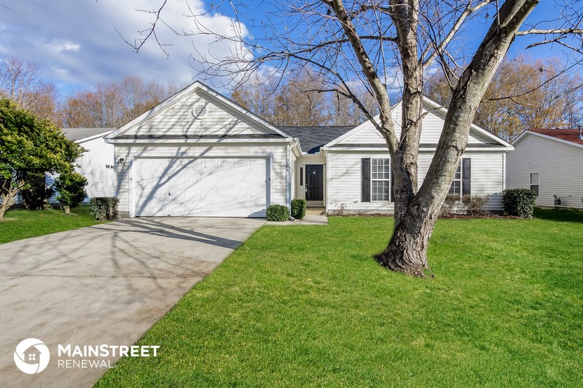 a white house with a driveway and a tree in the yard