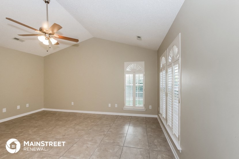 an empty living room with a ceiling fan and a window