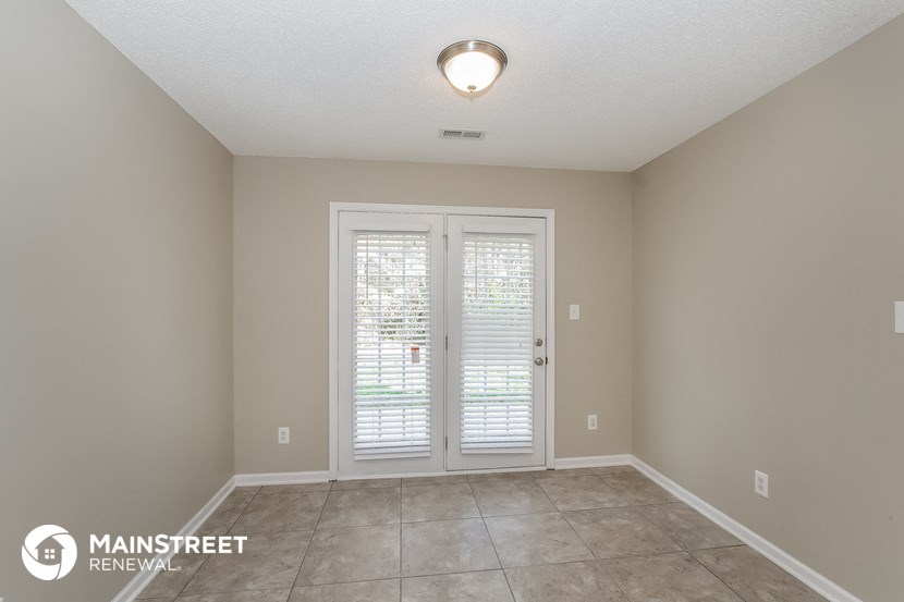 an empty living room with white doors and a tile floor