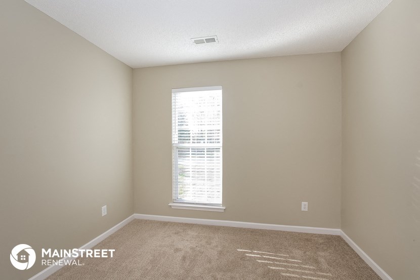an empty room with a window and carpet
