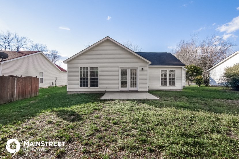 the front of a white house with a yard and grass