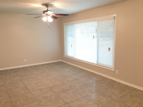 a living room with a large window and a ceiling fan