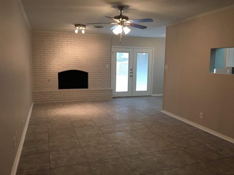 a living room with a brick fireplace and a ceiling fan