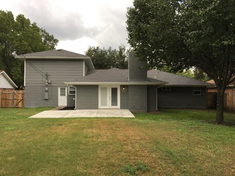 a gray house with a yard and a tree