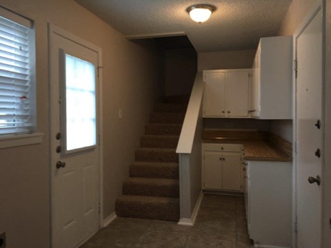 a small kitchen with stairs and a white door