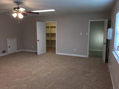 an empty living room with a ceiling fan and a closet