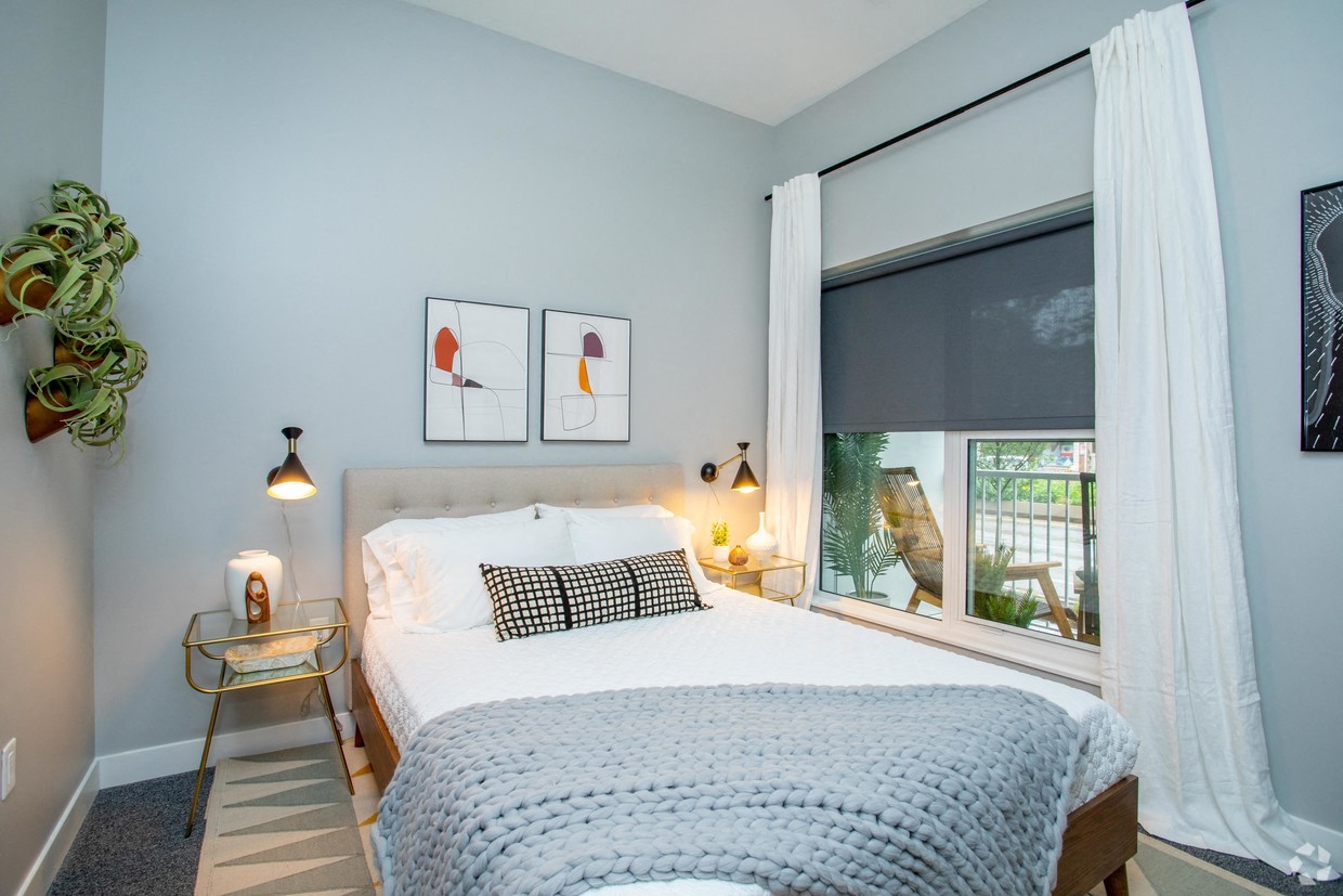 a bedroom with a bed and a window with white curtains