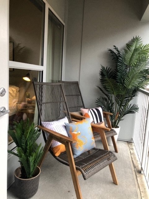 a small balcony with two chairs and potted plants