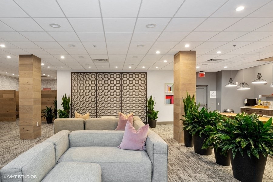 a large room with a large couch and potted plants